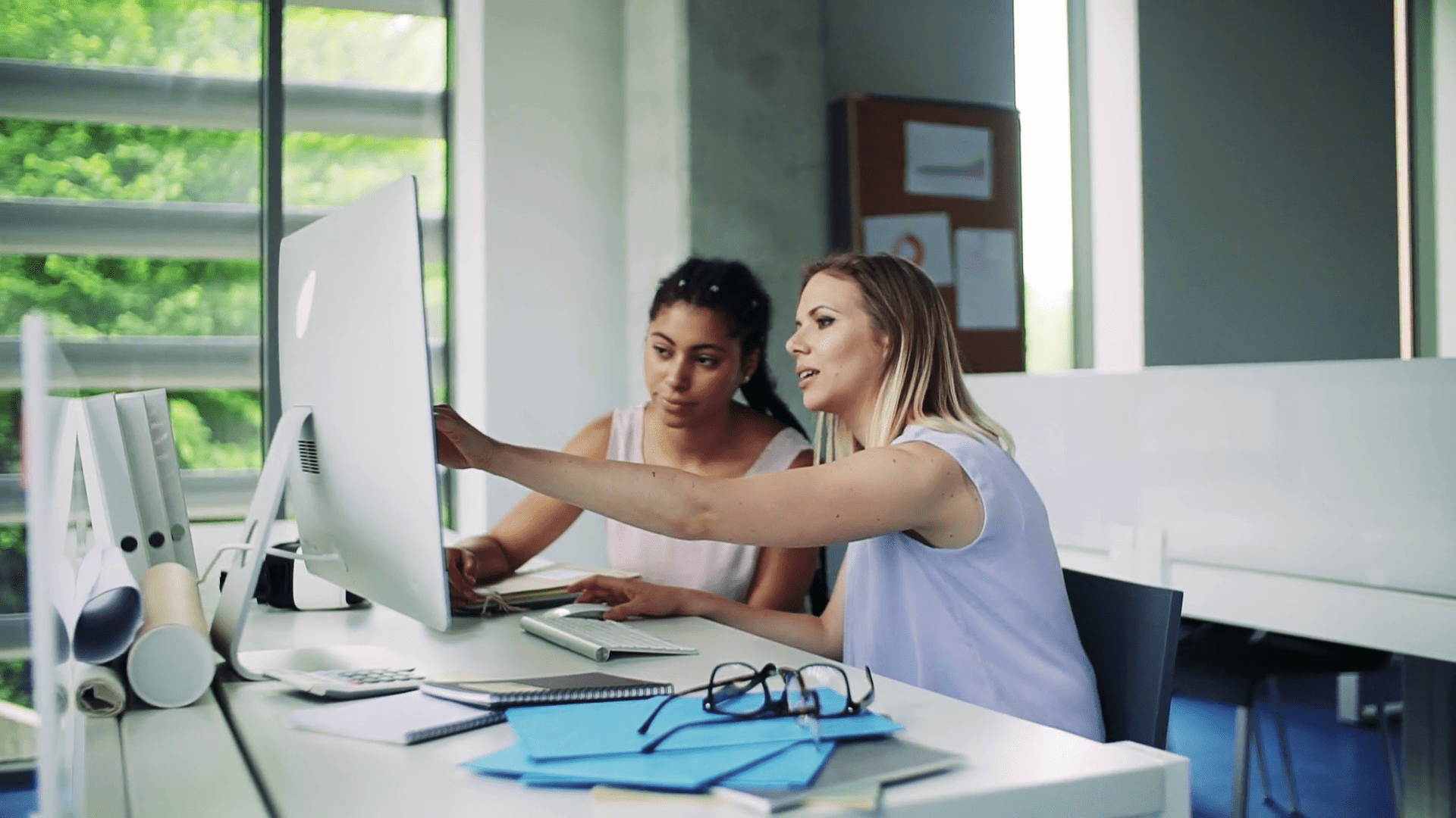 Two young women with computer sitting at the desk in the office working ZumaZip